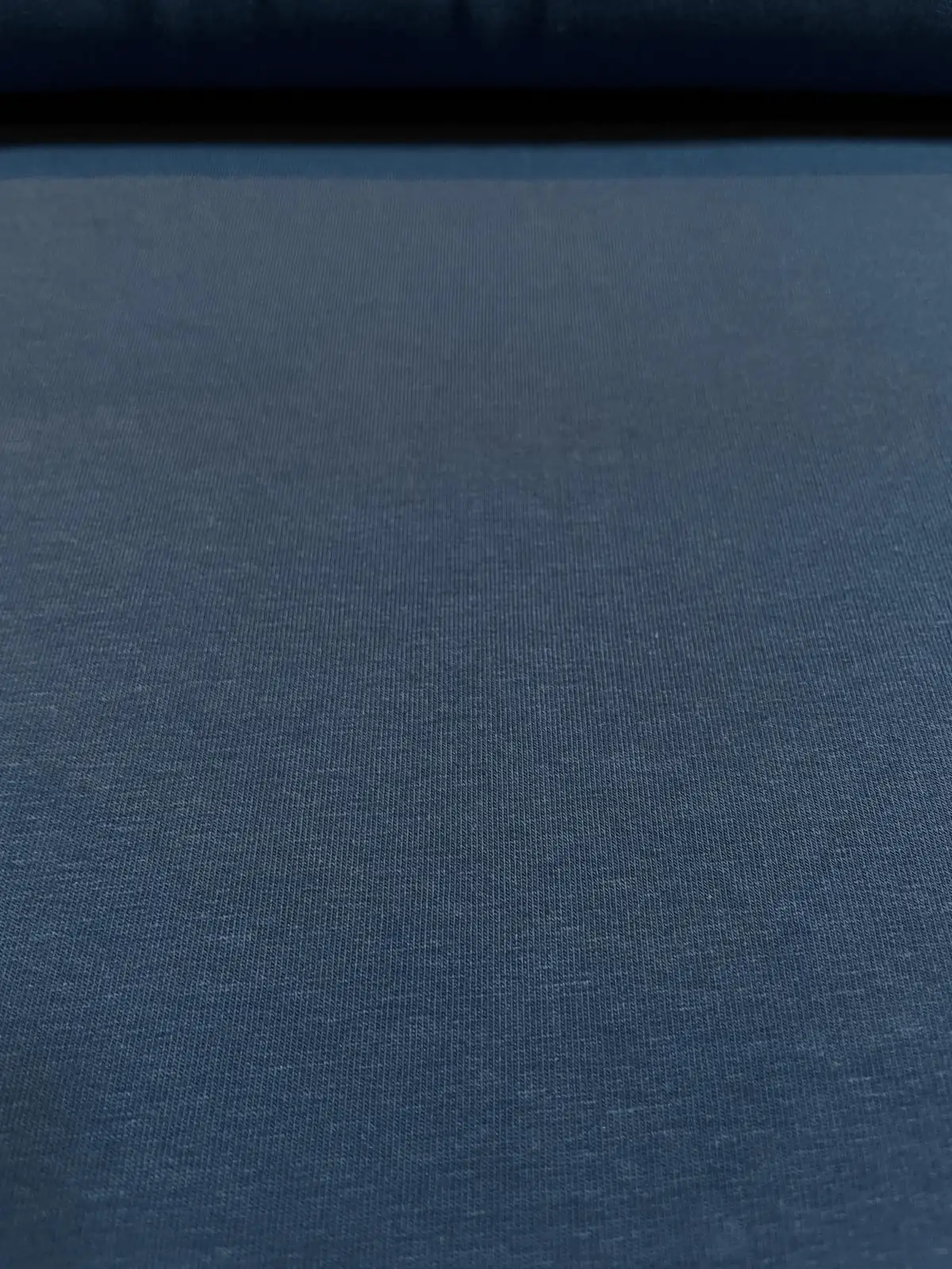 Nahaufnahme der glatten Vorderseite von dunkelblauem Sweatstoff als Meterware mit fein gestrickter Maschenstruktur für Hoodies und Pullover.