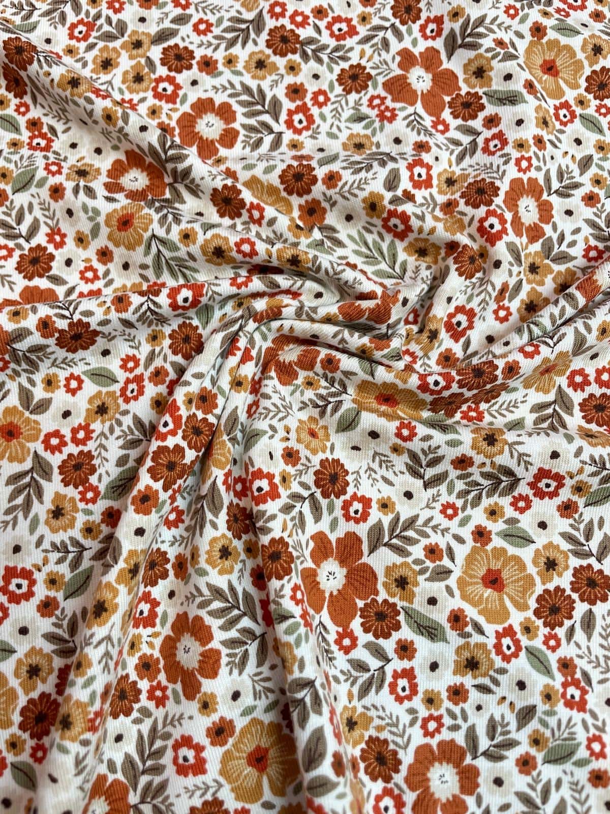Hochwertiger Jerseystoff mit dichtem floralem Retro-Muster in warmen Erdtönen wie Rost und Ocker, elastische Baumwoll-Meterware für Vintage-Liebhaber.