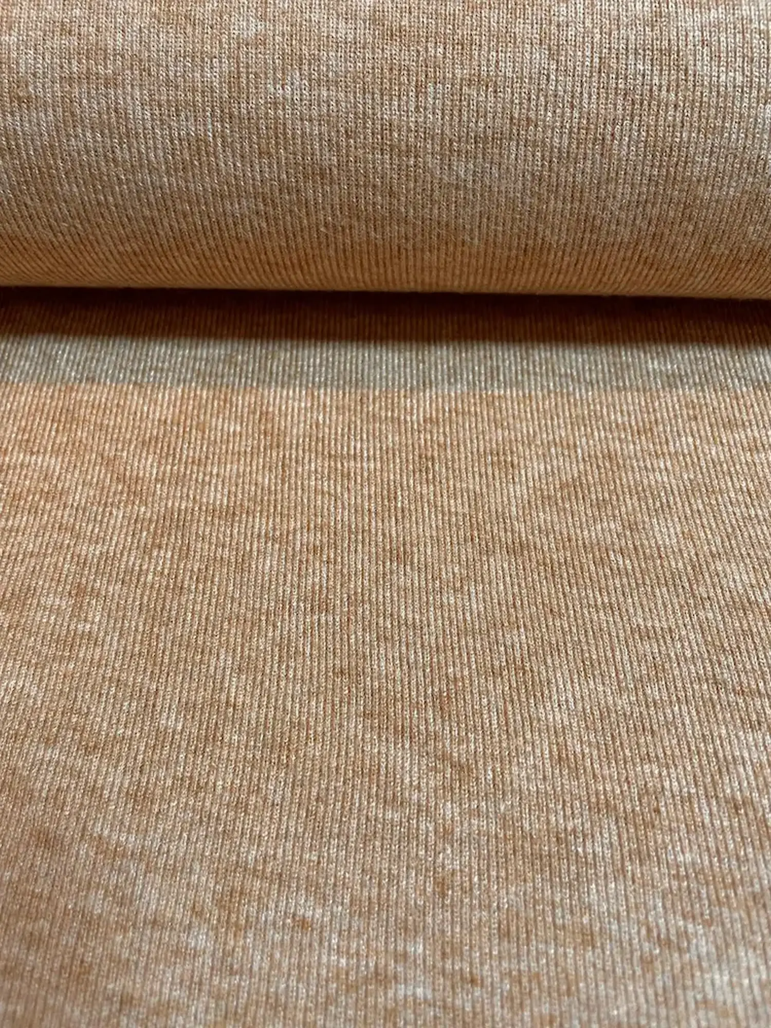 Ein weicher Feinstrickstoff mit dezenter vertikaler Rippenstruktur in einer warmen Zimt-Melange-Optik. Die Oberfläche zeigt ein harmonisches Spiel aus helleren und dunkleren Brauntönen. Ideal für gemütliche Cardigans, Pullover oder herbstliche Accessoires