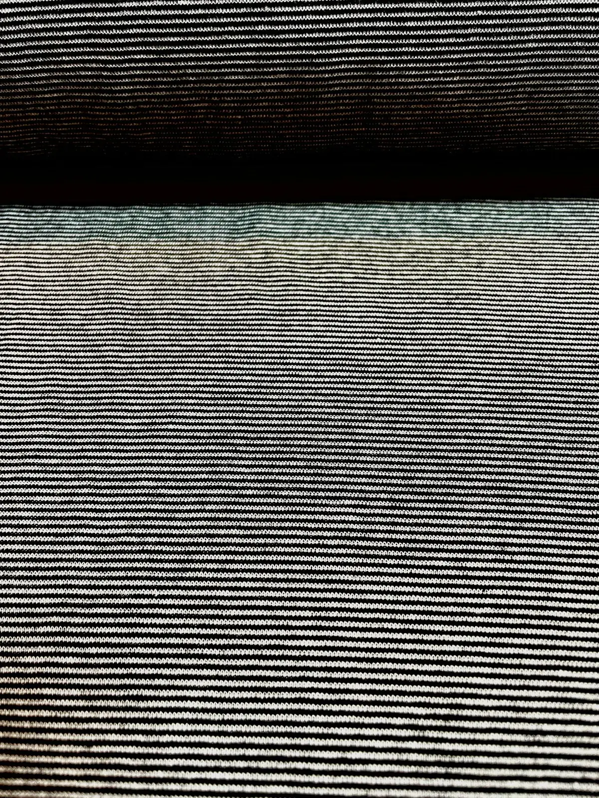 Feingestreifter Bündchenstoff in Schwarz-Weiß als elastische Schlauchware (Meterware) mit feinen horizontalen Ringelstreifen für Hoodies, T-Shirts und Bündchenabschlüsse.