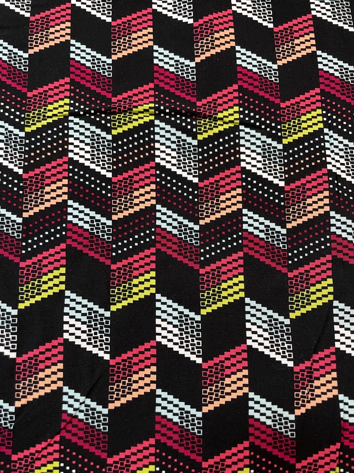Bedruckter Viskosestoff mit modernem Pixel-Zickzack-Muster in Rot, Gelb, Weiß und Mint auf schwarzem Grund – ideal für fließende Kleider und Blusen.