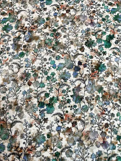 Weicher Jersey-Stoff mit einem dichten, floralen Allover-Print. Das Muster zeigt zarte Wiesenblumen und Blätter in verschiedenen Grün-, Braun- und Beigetönen auf hellem Grund. Perfekt für Kinderkleidung oder herbstliche Accessoires.