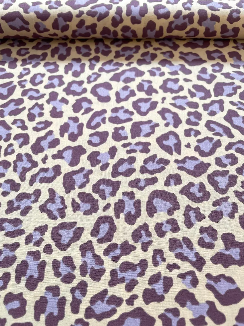 Hochwertiger Baumwollstoff mit modernem Leopardenmuster in Flieder und dunklem Lila auf hellem Hintergrund.