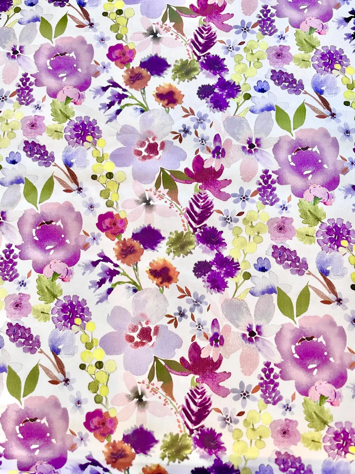Meterware Baumwoll-Satin mit malerischem Blumenmuster in Violett, Flieder und Erdtönen, flach liegend auf Holzgrund neben Lavendelzweigen.