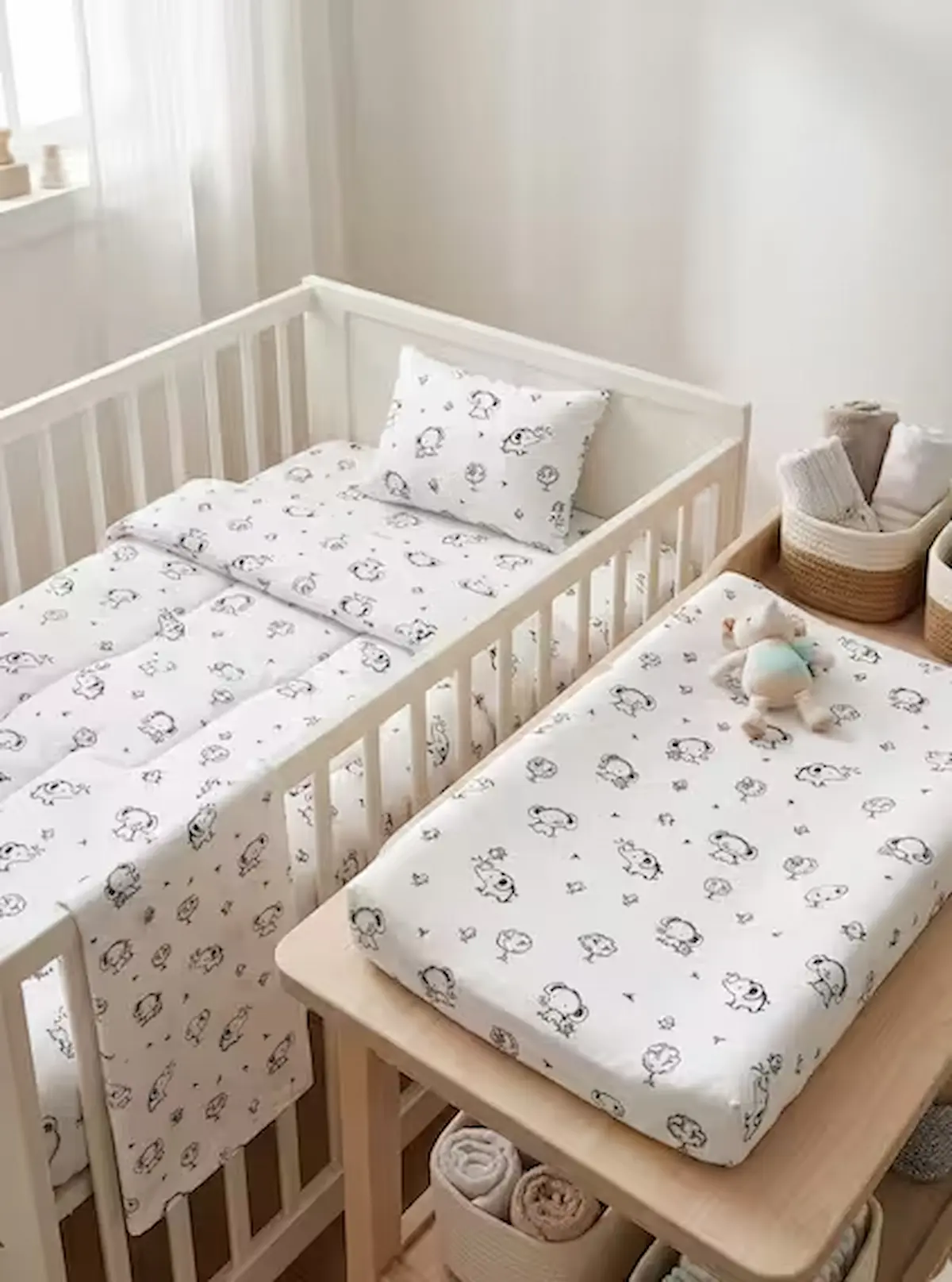 Zertifizierter Bio-Baumwoll-Popeline-Stoff als Meterware in Weiß mit feinen schwarzen Konturen von kleinen Elefanten und Bäumen, genäht als Babybettwäsche und Wickelauflagenbezug.