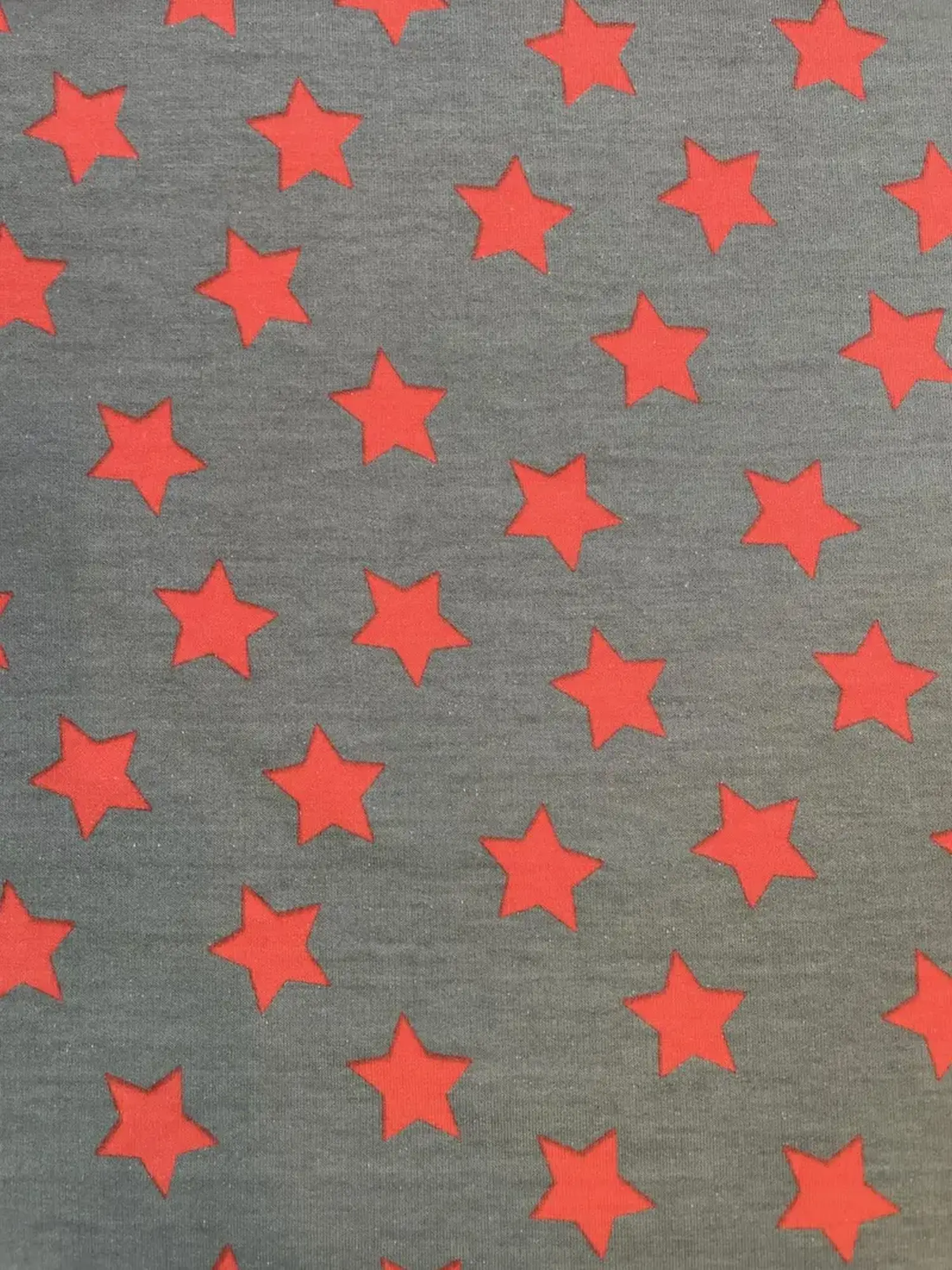 Grauer Sweatstoff als Meterware mit Allover-Print aus kleinen roten Sternen, weiche Abseite, ideal für Kinderkleidung.