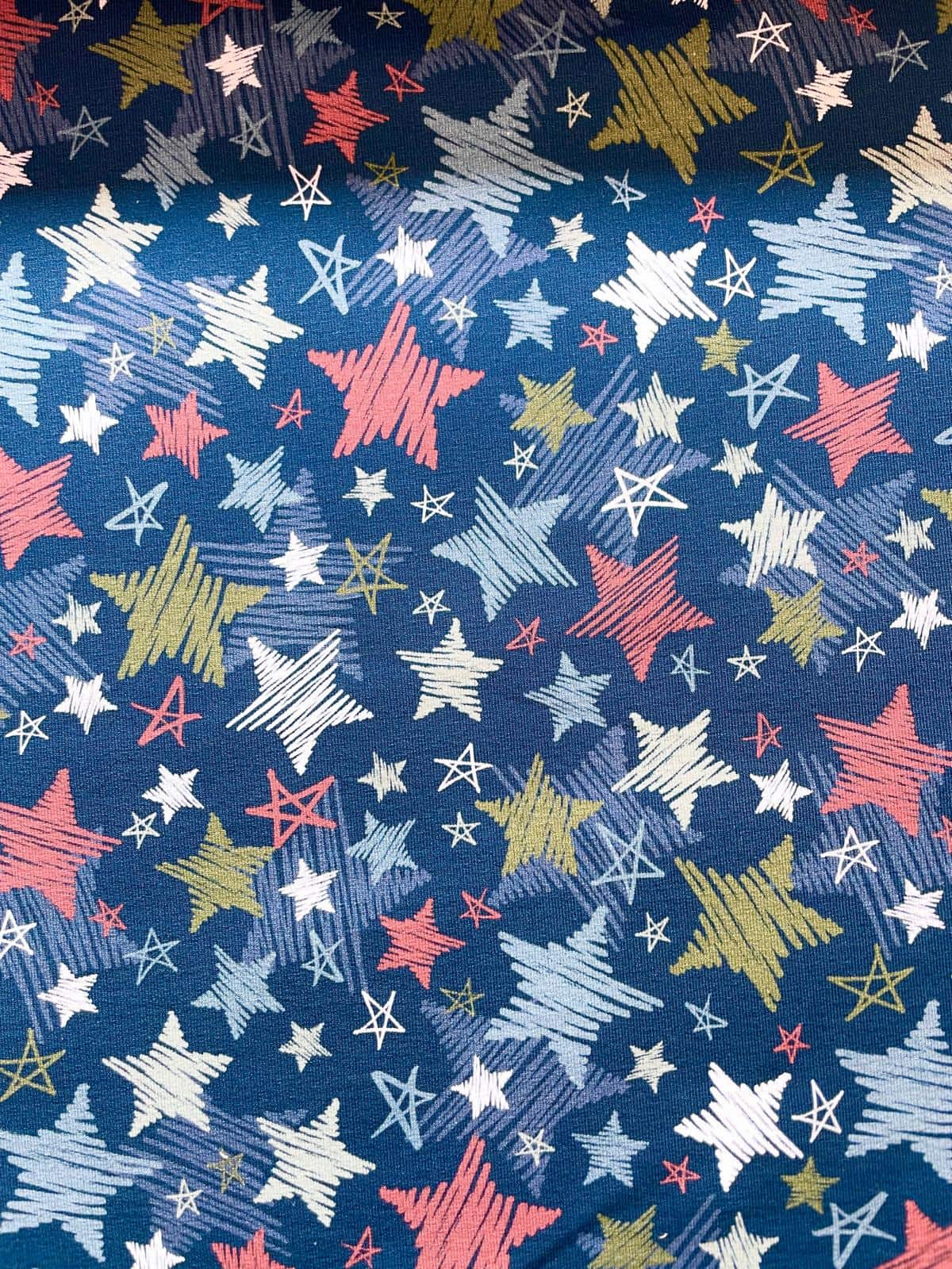 Hochwertiger French Terry Stoff in Dunkelblau bedruckt mit bunten Sternen in Kreide-Optik, weiche Sommersweat-Qualität für Kinderbekleidung.