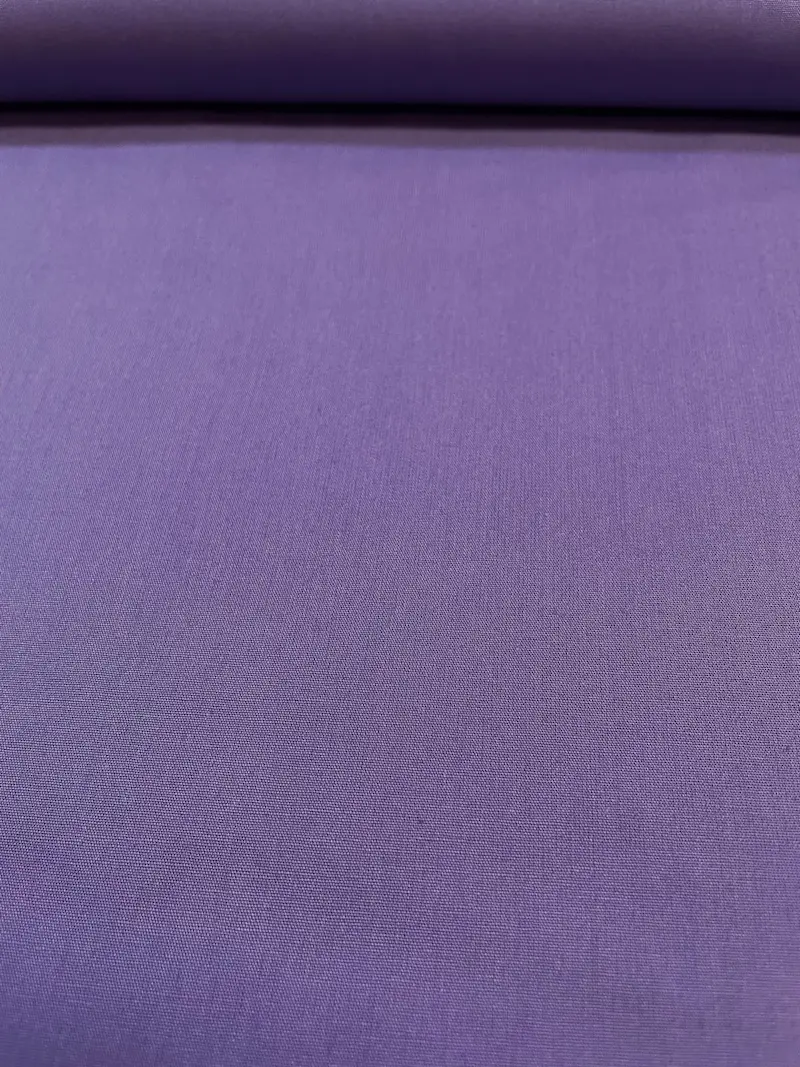 Glatt präsentierter, unelastischer Baumwoll-Popeline Stoff als Meterware in kräftigem Violett, der am oberen Rand ordentlich über eine Stoffrolle liegt und eine feine, dichte Webstruktur zeigt.