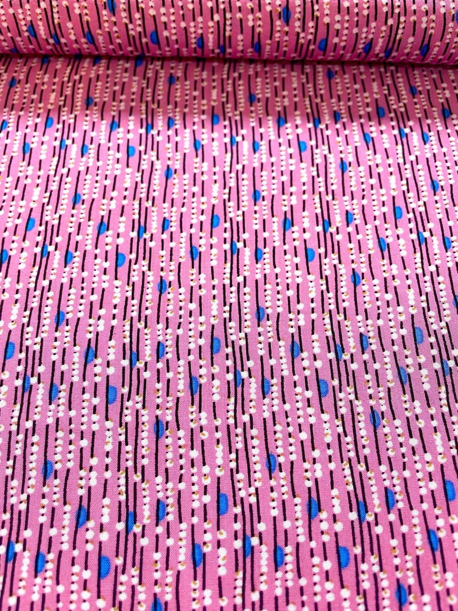 Nahaufnahme eines pinken Viskosestoffs mit vertikalem Linienmuster, weißen Punkten und blauen Details.