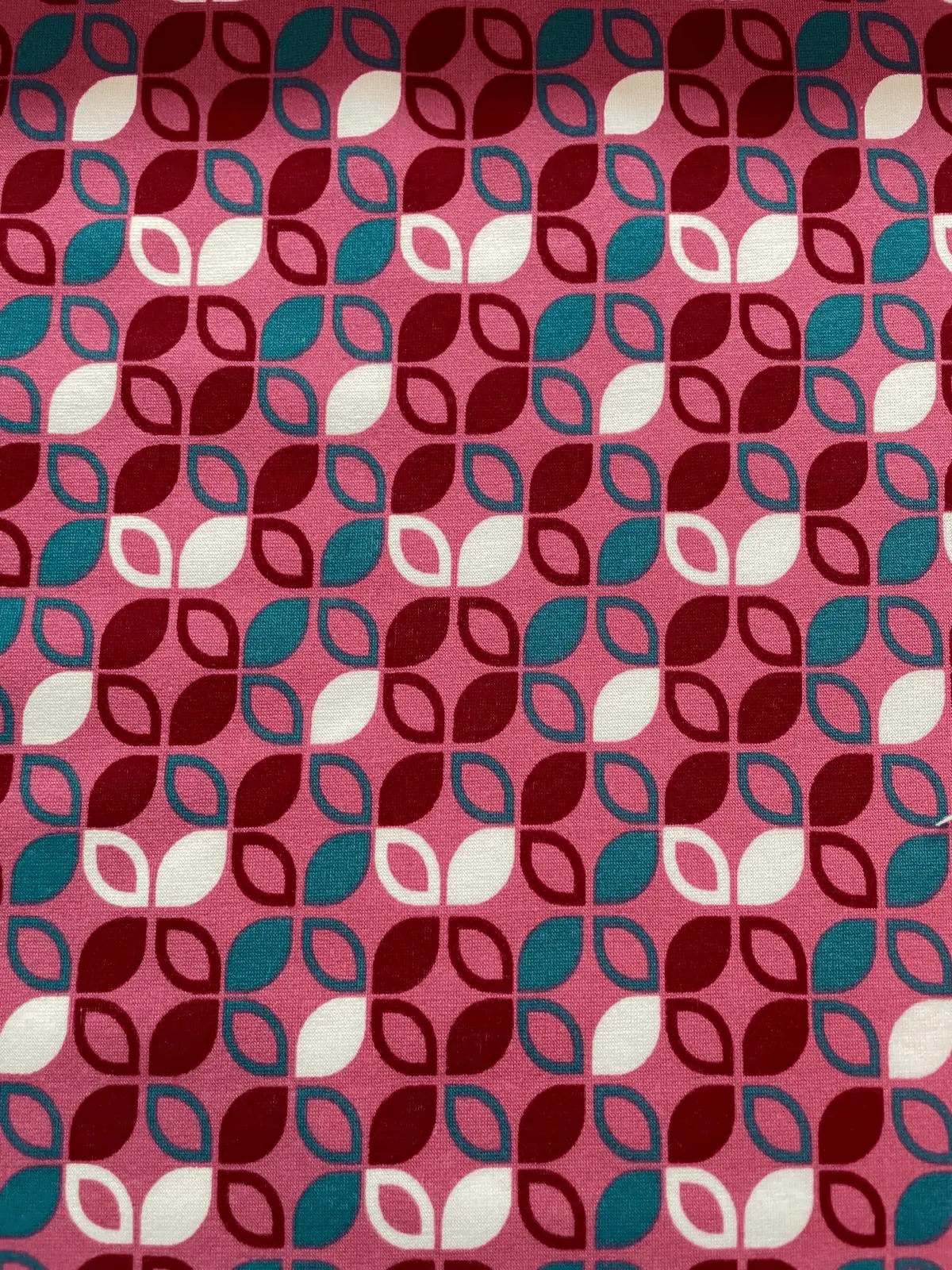 Kuscheliger Alpenfleece-Stoff als Meterware mit einem geometrischen Retro-Muster aus Blättern und Kreisen in Pink, Bordeaux, Petrol und Weiß.