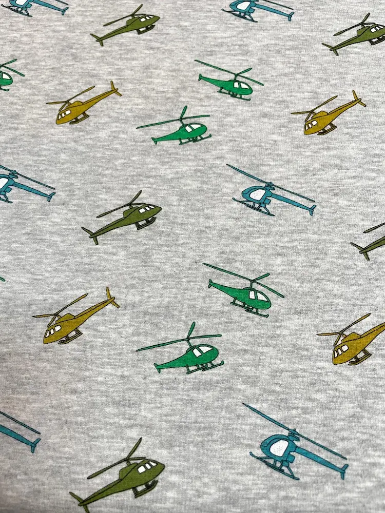 Weicher Alpenfleece in Grau Meliert mit bunten Hubschrauber-Motiven in Grün, Blau und Gelb; Doubleface-Qualität mit flauschiger Rückseite, ideal für warme Kinder-Hoodies und Jacken.