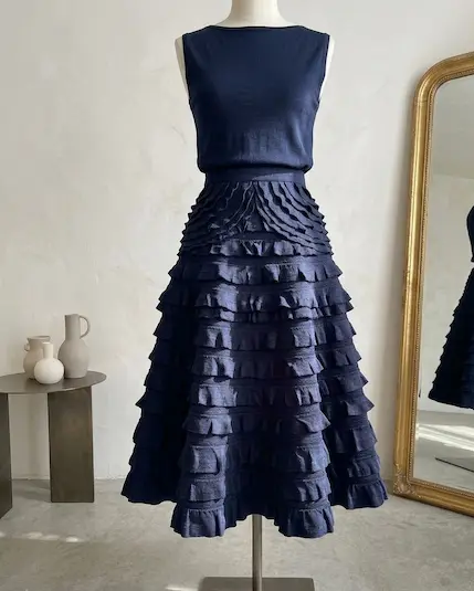 Elegantes ärmelloses Kleid in Marineblau mit einem weit ausgestellten Rock aus strukturiertem Rüschchen-Jersey auf einer Schneiderpuppe.