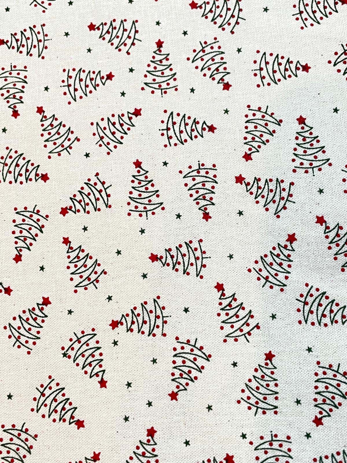 Festlicher Baumwollstoff als Meterware mit gezeichneten Tannenbäumen, roten Christbaumkugeln und roten Sternen auf hellem weißem Hintergrund.