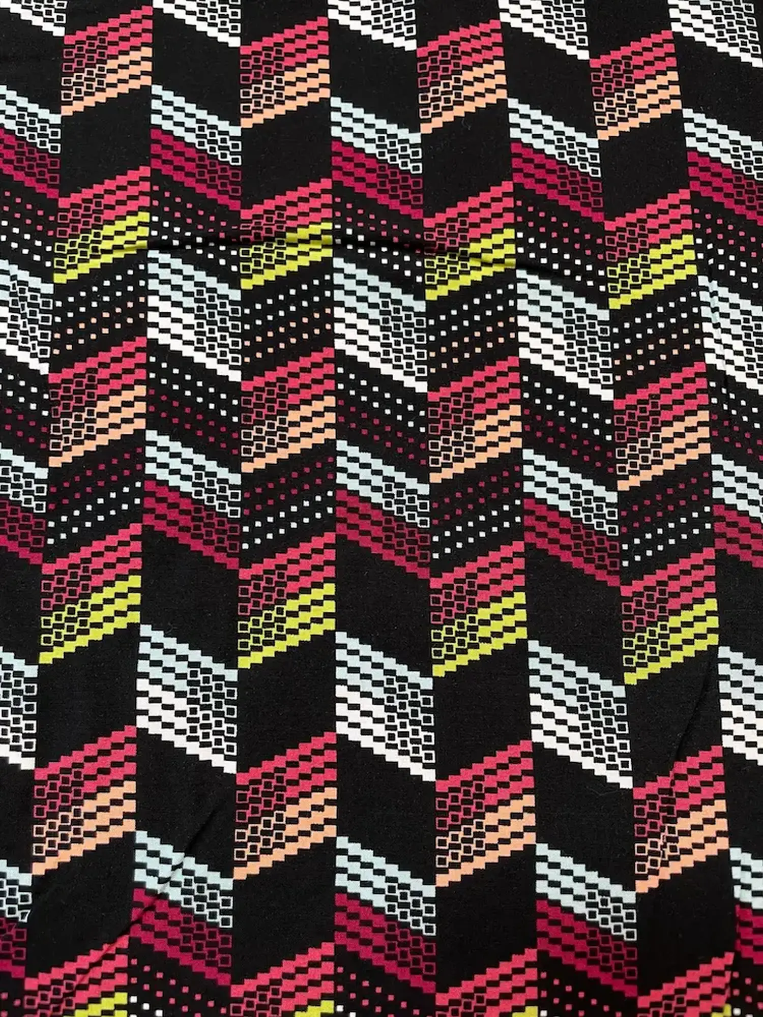 Bedruckter Viskosestoff mit modernem Pixel-Zickzack-Muster in Rot, Gelb, Weiß und Mint auf schwarzem Grund – ideal für fließende Kleider und Blusen.