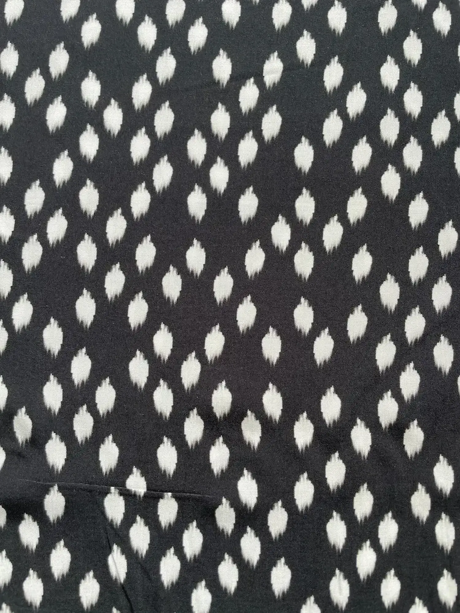 Hochwertiger Viskosestoff mit 15% Polyamid-Anteil. Das Muster zeigt weiß verschwommene Punkte im Ikat-Stil auf schwarzem Hintergrund. Der Stoff liegt flach und zeigt eine feine Gewebestruktur.