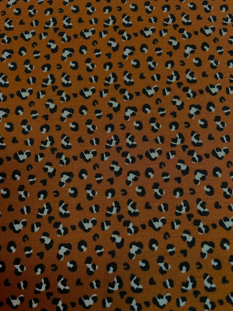 Elastischer Baumwolljersey-Stoff mit modernem Leopard-Print auf ockerfarbenem Grund. Weicher Jersey mit hohem Tragekomfort, ideal für Kinderkleidung, Shirts, Leggings und Beanies.