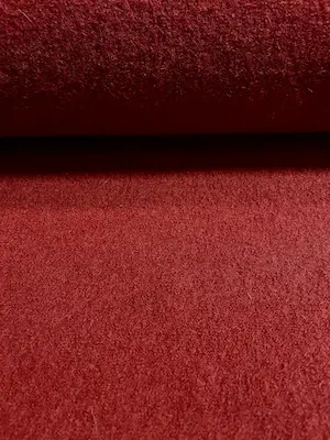Hochwertiger Walkstoff aus 100% Schurwolle in einem tiefen Rostrot, Nahaufnahme der dichten, gefilzten Textur.