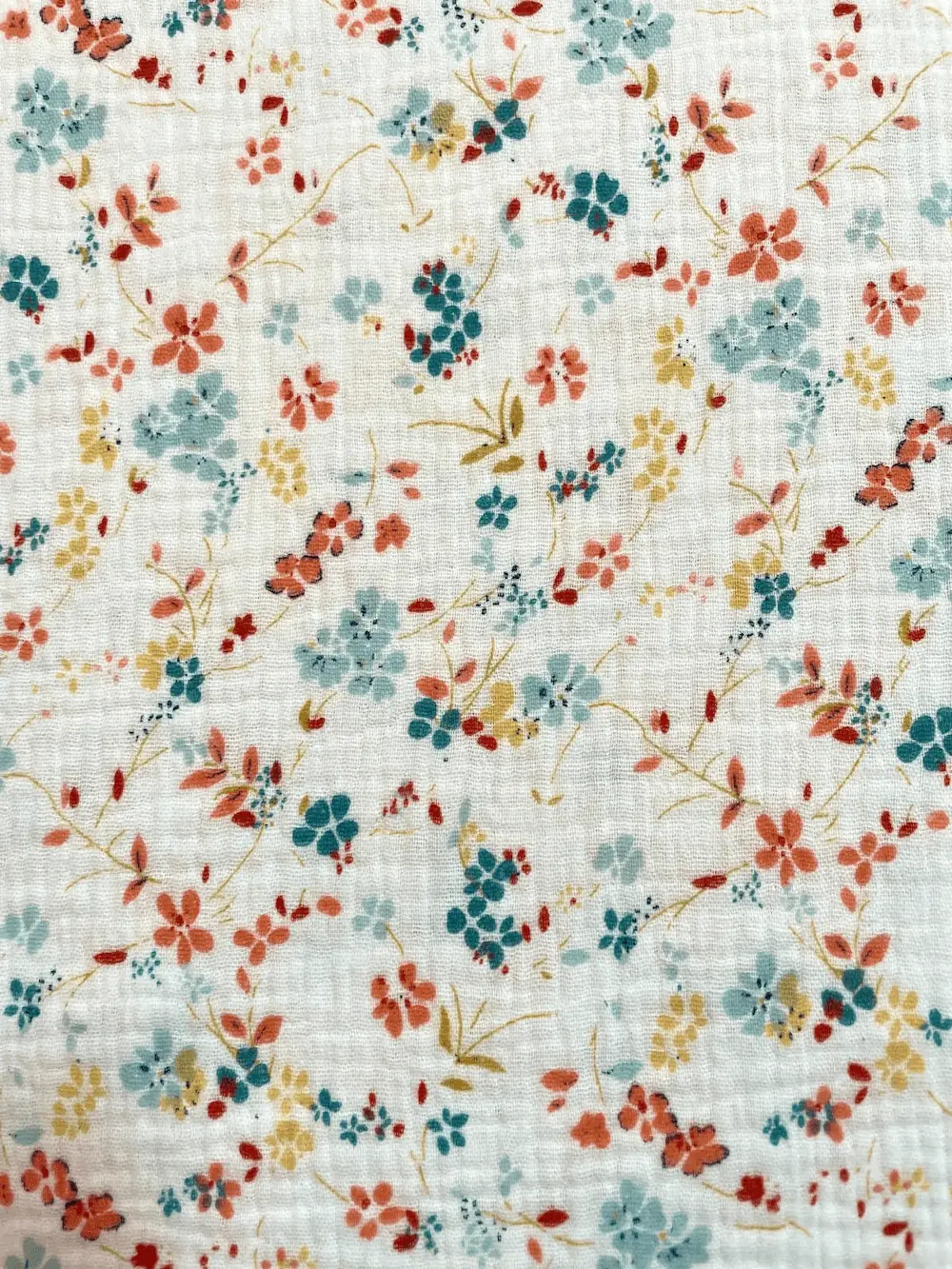 Weißer Musselin-Stoff mit herbstlichen kleinen Blumen in Rostrot, Senf und Petrol, 100% Baumwolle mit Crinkle-Struktur.