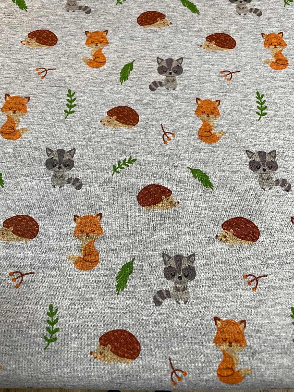 Weicher Alpenfleece in Grau Meliert mit niedlichen Waldmotiven wie Fuchs, Waschbär und Igel sowie grünen Blättern; perfekt für Baby- und Kinder-Winterbekleidung.
