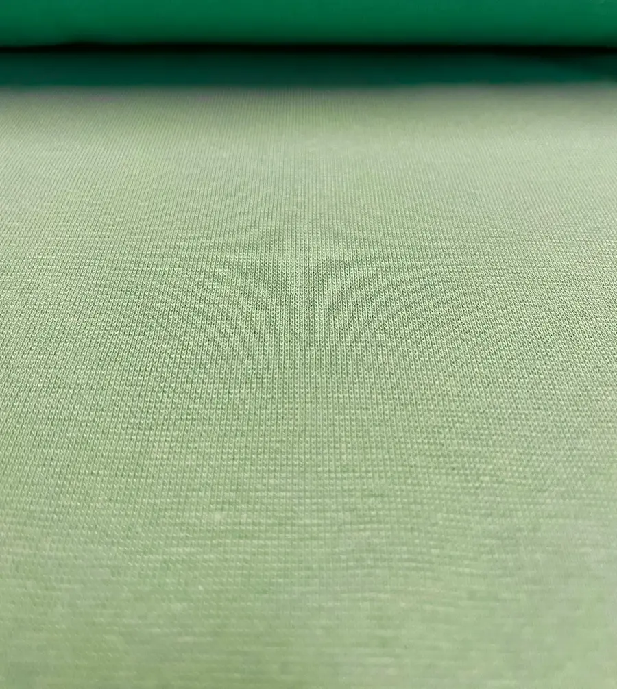 Nahaufnahme eines fein gerippten Bündchenstoffes in Uni Salbeigrün, ideale Schlauchware für Ärmel- und Halsabschlüsse.