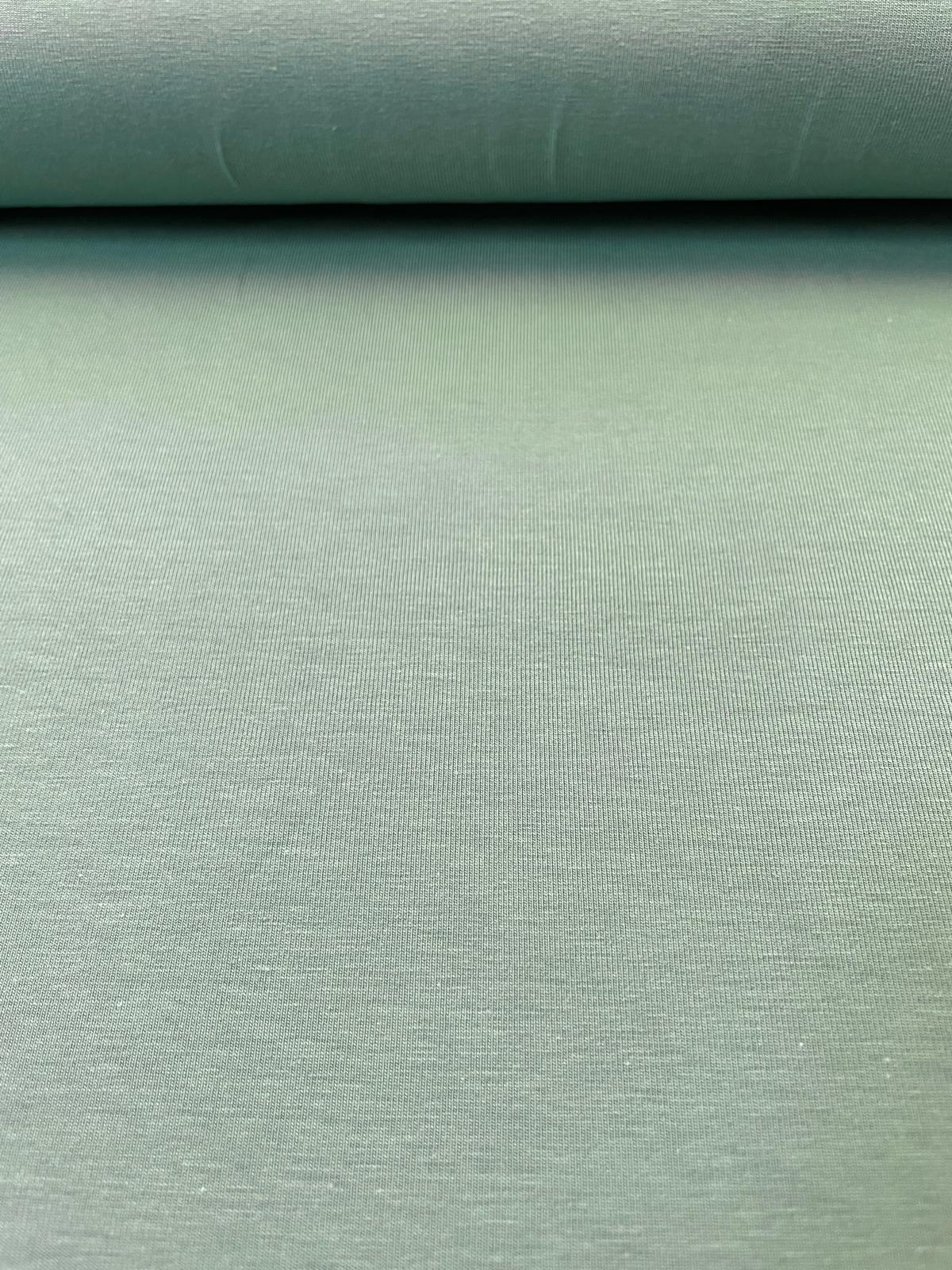 Nahaufnahme von weichem, meliertem Jersey-Stoff in Salbeigrün auf einer Rolle, 200g/m² Qualität für Kleidung.