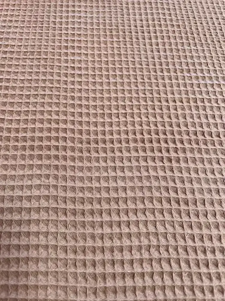 Nahaufnahme von braunem Waffelpique Stoff als Meterware mit charakteristischer Waffelstruktur für Decken, Handtücher und herbstliche DIY-Projekte.