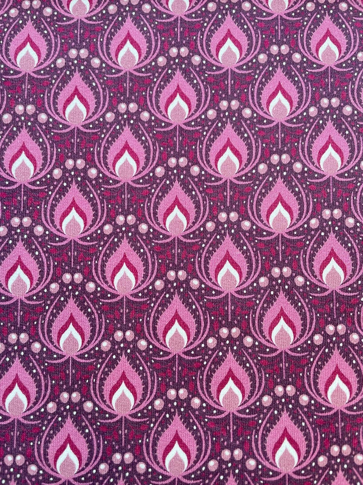 Kuscheliger Alpenfleece-Stoff als Meterware mit einem eleganten Allover-Muster aus floralen Ikat-Ornamenten und Punkten in Beere, Rosa und Violett.