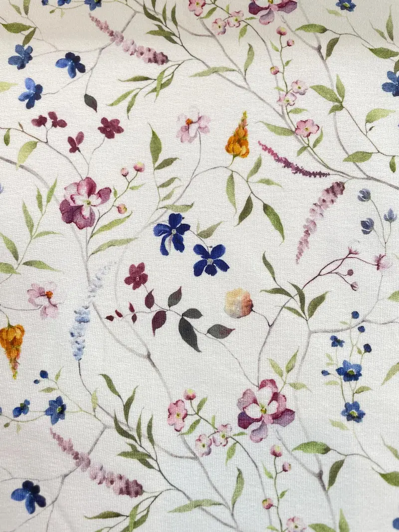 Floraler French Terry Stoff mit buntem Aquarell-Blumenmuster auf weißem Hintergrund als Meterware