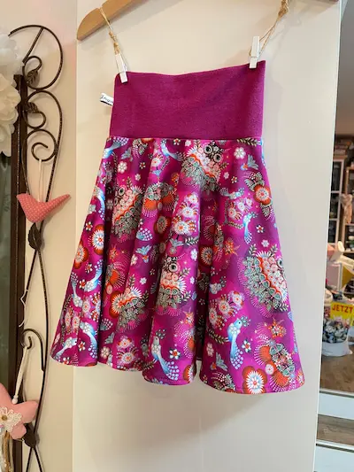 Handgenähter Kinderrock aus Jersey mit buntem Eulen-Folklore-Muster in Magenta. Ausgestellter Rock mit breitem elastischem Bündchen, präsentiert an einem Kleiderbügel