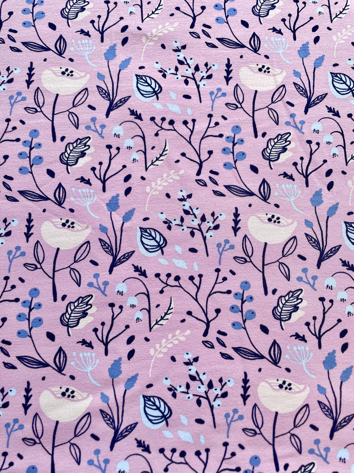 Nahaufnahme eines fliederfarbenen Sommersweat-Stoffes mit einem feinen Muster aus dunkelblauen Zweigen, kleinen Beeren und weißen Blüten, ideal für Kinder- und Babybekleidung.