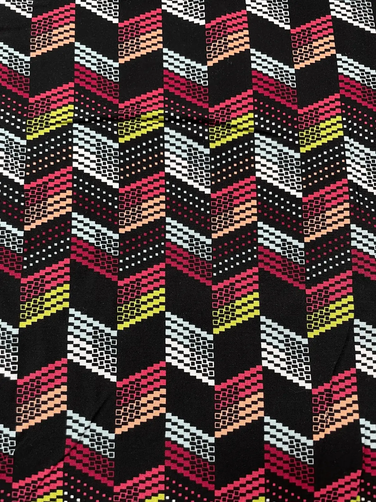 Bedruckter Viskosestoff mit modernem Pixel-Zickzack-Muster in Rot, Gelb, Weiß und Mint auf schwarzem Grund – ideal für fließende Kleider und Blusen.