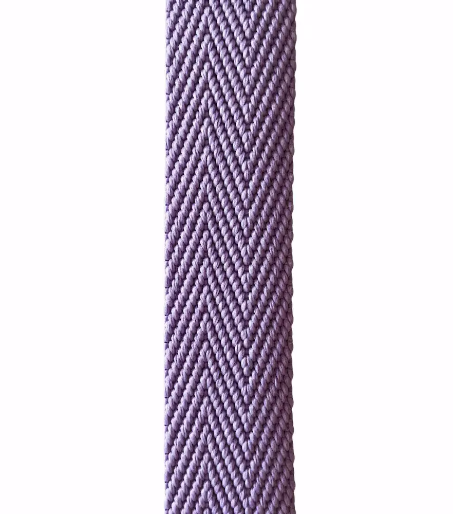 Nahaufnahme von einem fliederfarbenen Gurtband mit 3 cm Breite und elegantem Fischgrat-Muster vor weißem Hintergrund, Meterware für Taschenriemen.