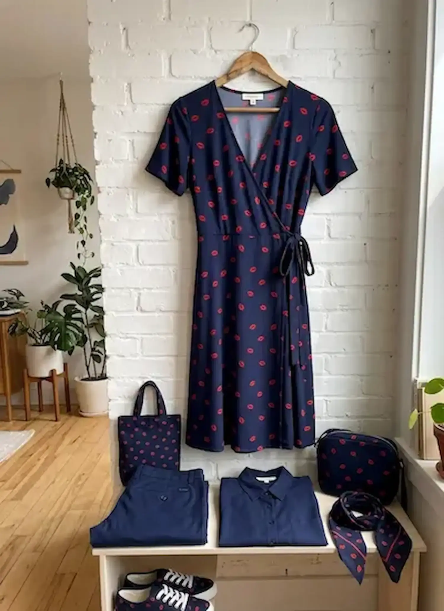 Fließende Viskose-Webware als Meterware in Marineblau mit roten Kussmund-Print, präsentiert als Wickelkleid und passende Accessoires wie Tasche und Schal.