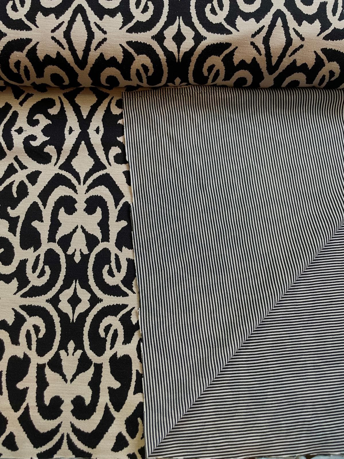 Elegante Schößchen-Bluse aus Viskose-Mix Stoff mit barockem Ornament-Muster in Schwarz und Beige auf einer Schneiderpuppe in einem Nähatelier.