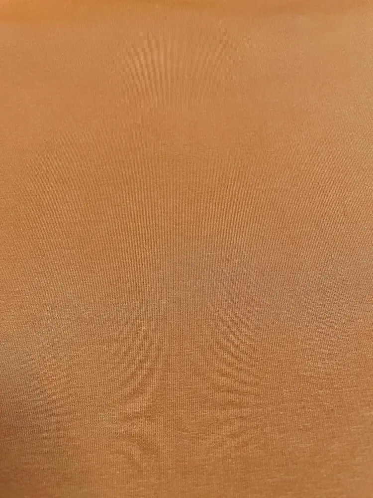 Ein hochwertiger French Terry Sommersweat in einem warmen Rostbraun bzw. Terracotta. Die glatte, feine Strickoberfläche des elastischen Baumwollstoffes ist im Detail erkennbar. Ein idealer Uni-Kombistoff für herbstliche und zeitlose Bekleidungsprojekte.