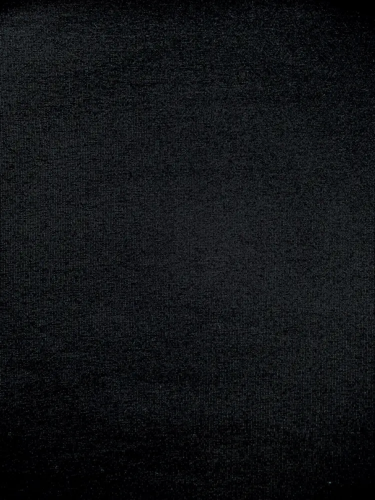 Nahaufnahme von elastischem Baumwolljersey Stoff in Uni Schwarz mit feiner Strickstruktur.