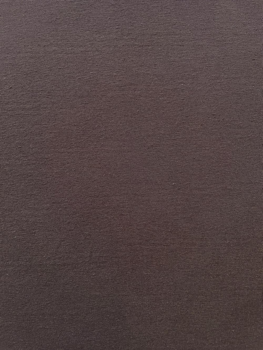 Nahaufnahme der feinen Strickstruktur eines dunkelbraunen Jersey-Stoffes in Mocca, blickdichte Qualität aus 92% Baumwolle und 8% Elasthan.