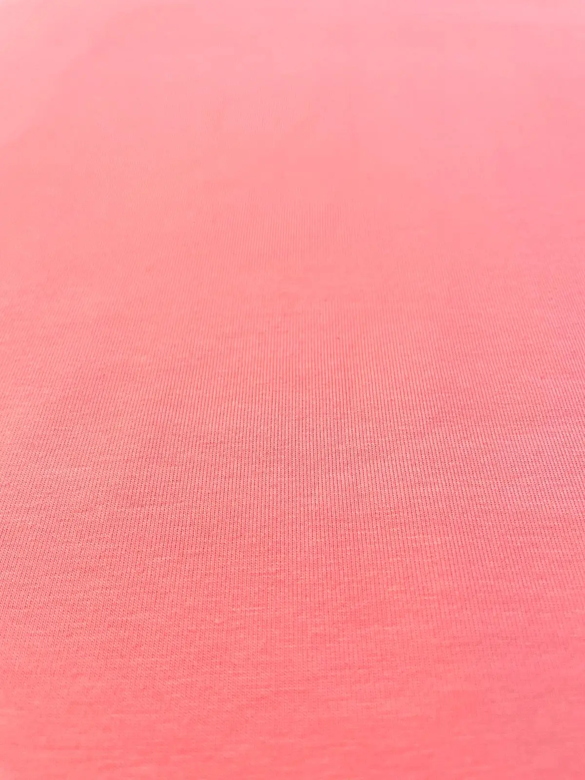 Nahaufnahme eines lachsfarbenen Baumwolljerseys mit feiner Maschenstruktur, 159 cm breit, ideal für Kinderkleidung und Damenmode.