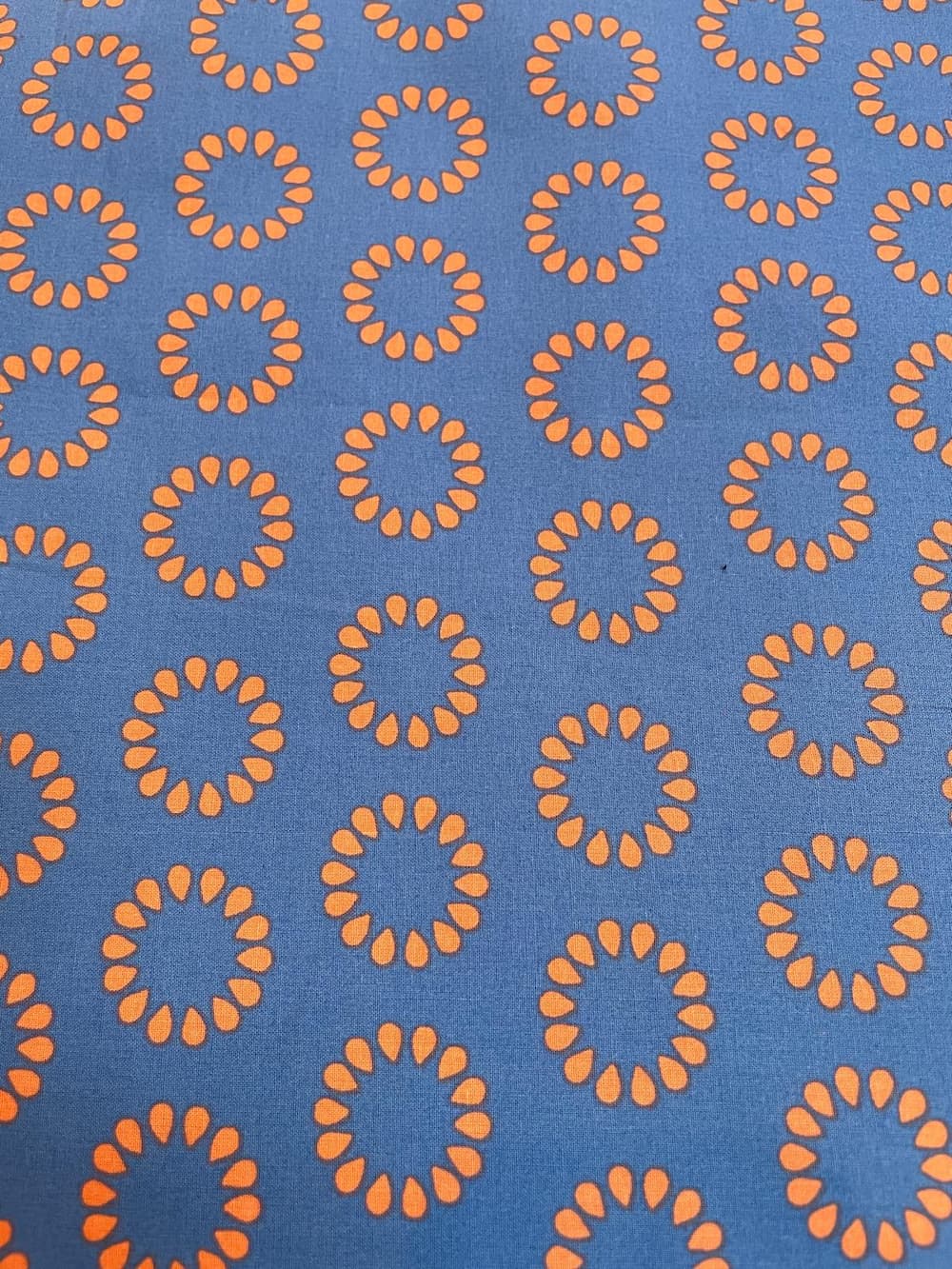 Beschichtete Baumwolle in Blau mit grafischem Retro-Muster aus orangefarbenen Kreisen – wasserabweisend.