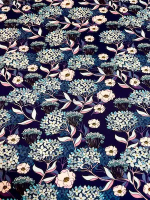 Detailgetreue Draufsicht eines Jersey-Stoffs mit Hortensien-Motiv. Das Muster zeigt stilisierte hellblaue und beerenfarbene Blüten auf dunkelblauem Grund. Klare Darstellung des floralen Drucks für Nähprojekte.