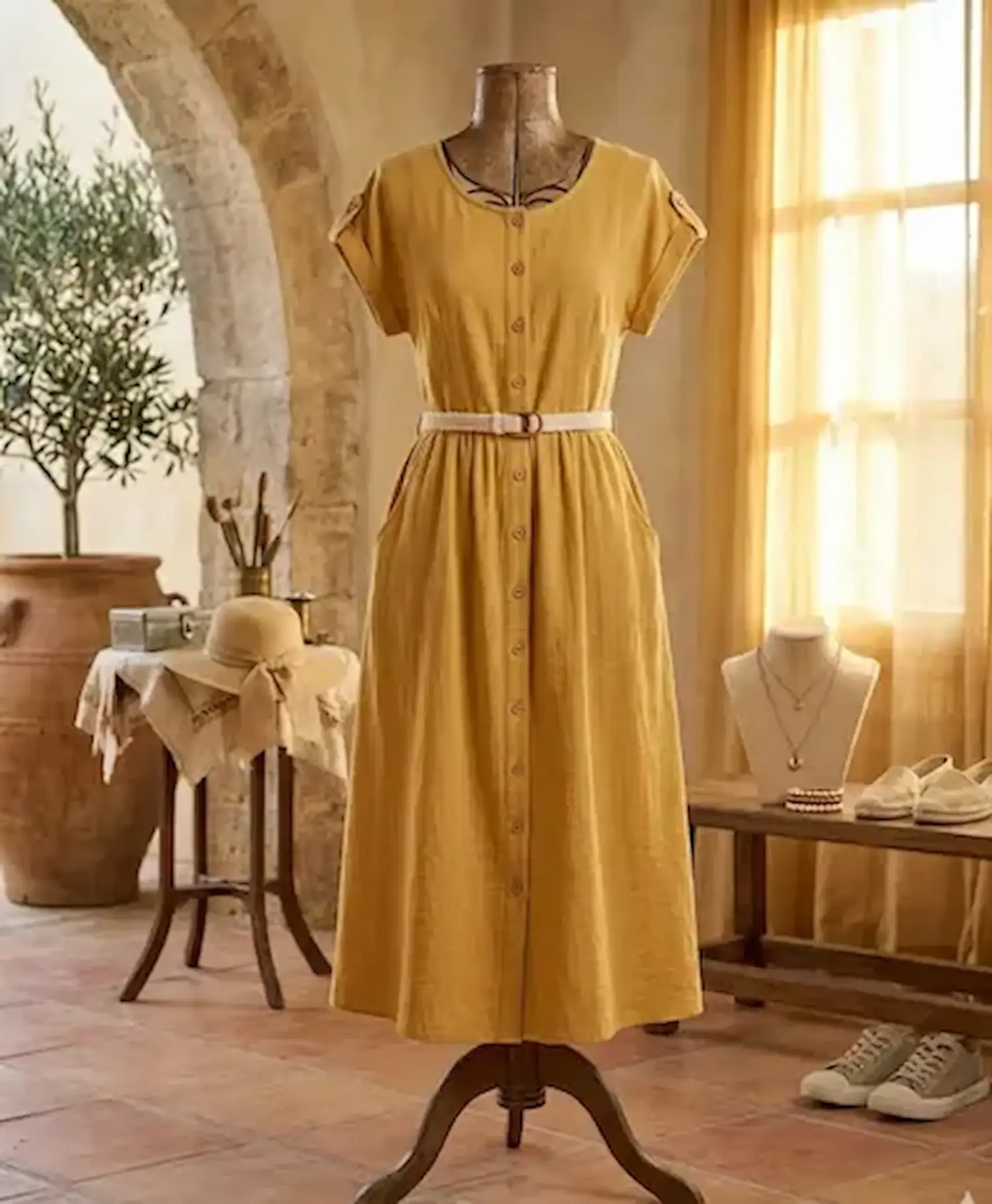 Ärmelloses Sommerkleid aus uni senfgelber Musselin-Meterware auf einer Schneiderpuppe in mediterranem Ambiente