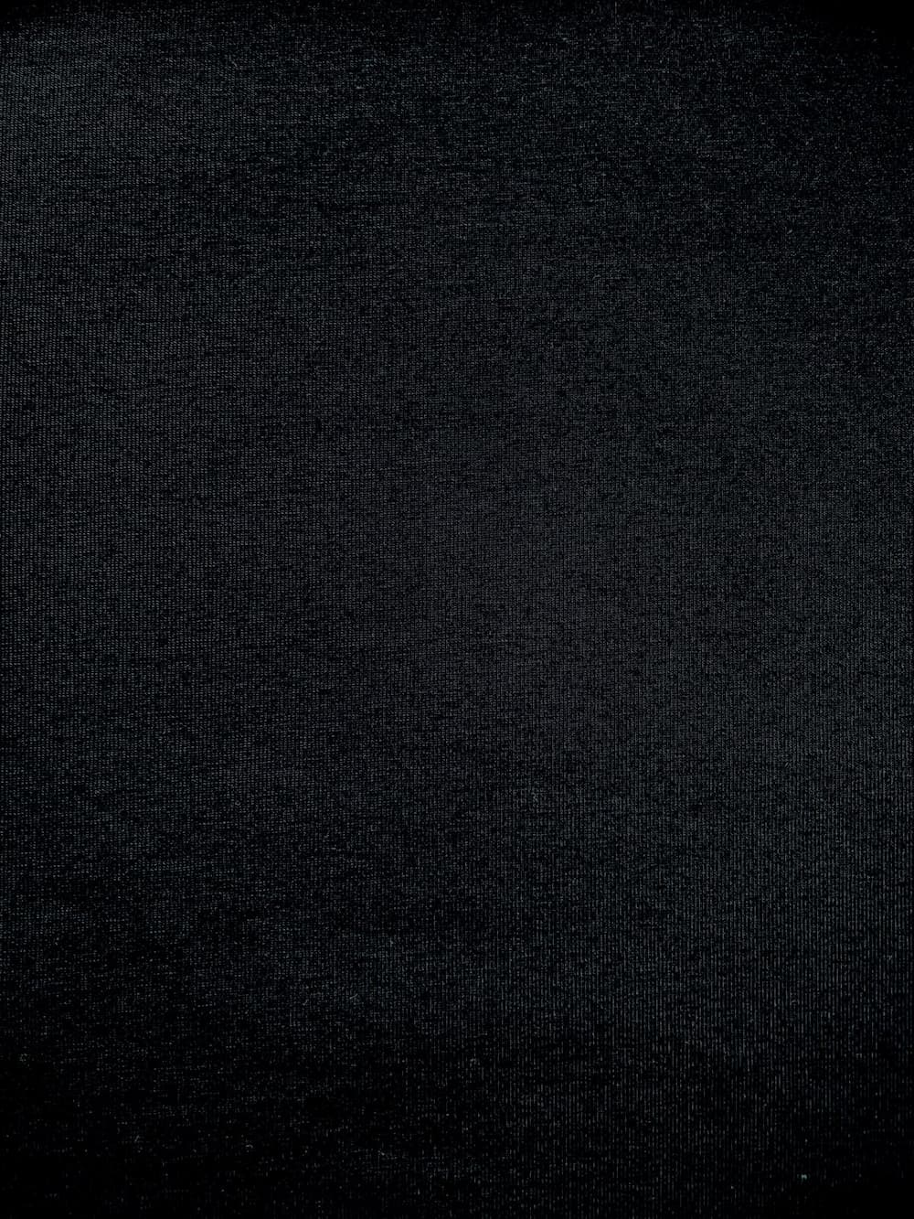 Nahaufnahme von elastischem Baumwolljersey Stoff in Uni Schwarz mit feiner Strickstruktur.