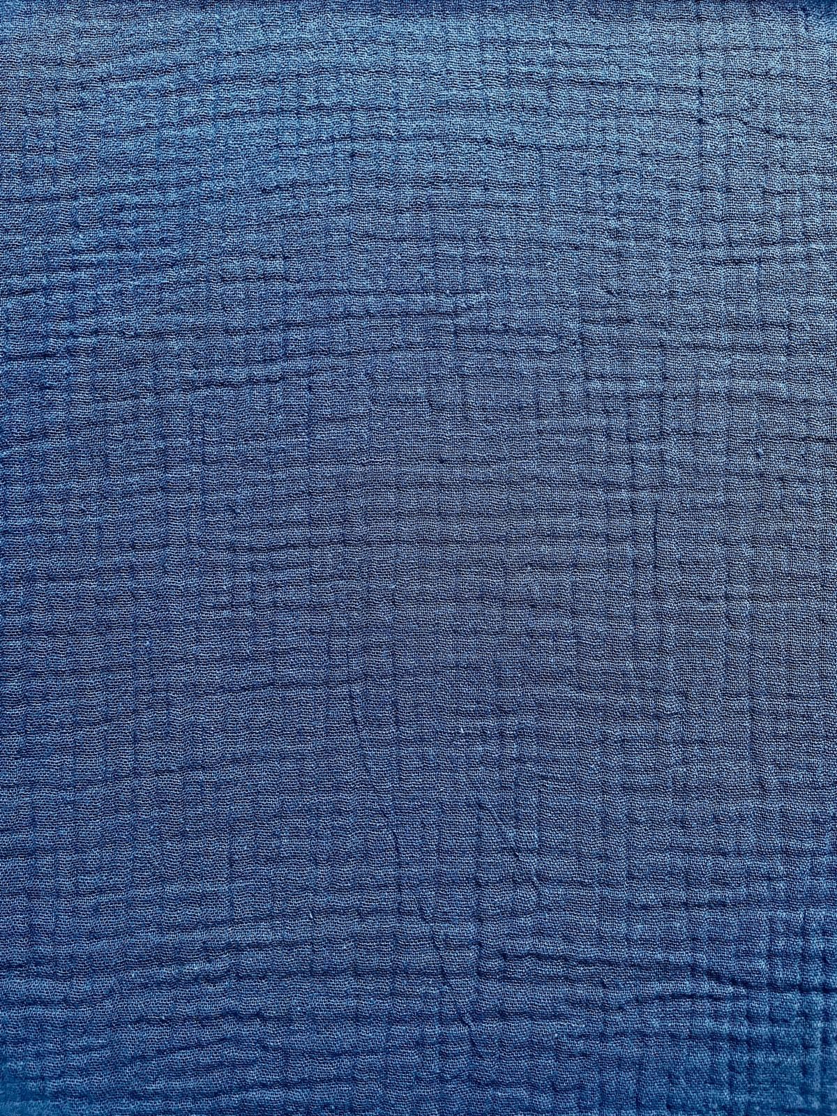 Nahaufnahme von mittelblauem Musselin-Stoff aus reiner Baumwolle mit charakteristischer Crinkle-Optik.