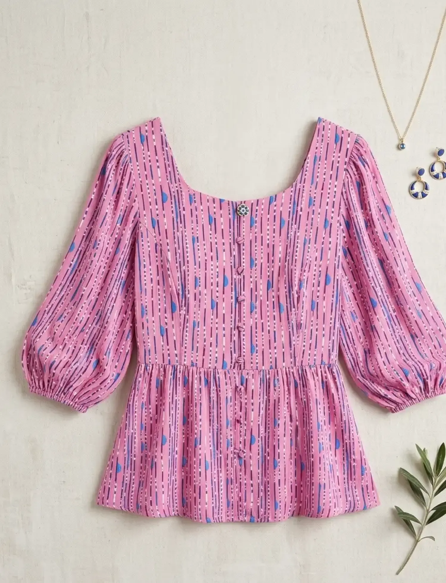 Feminine Schößchen-Bluse aus weich fließender Viskose Webware mit grafischem Streifenmuster in Rosa und Blau.