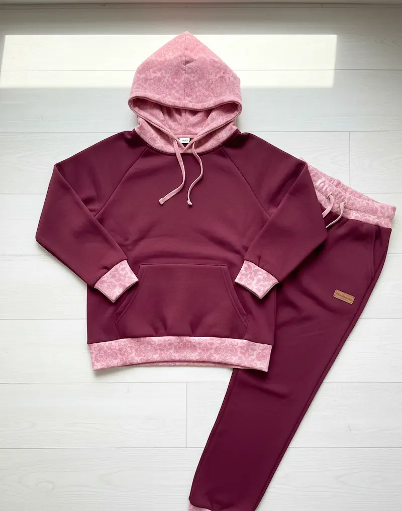 Bündchenware als Meterware mit fein gemustertem Blumenmuster in Rosa, vernäht als Kapuze, Ärmelbündchen und Saum an einem weinroten Hoodie und einer Jogginghose.