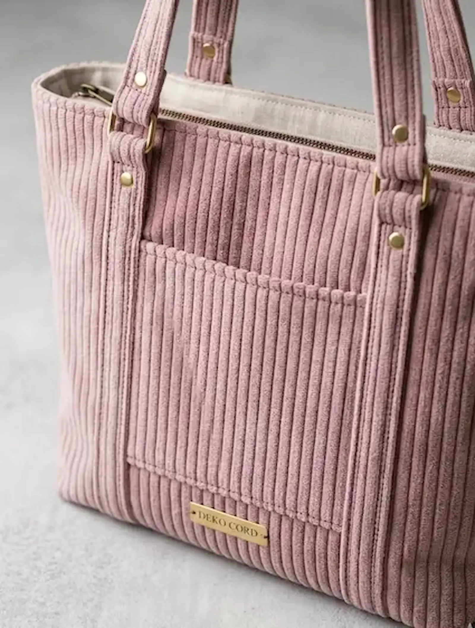 Detailaufnahme von hochwertigem Breitcord Stoff in Altrosa, verarbeitet zu einer Tasche mit goldenen Metalldetails.