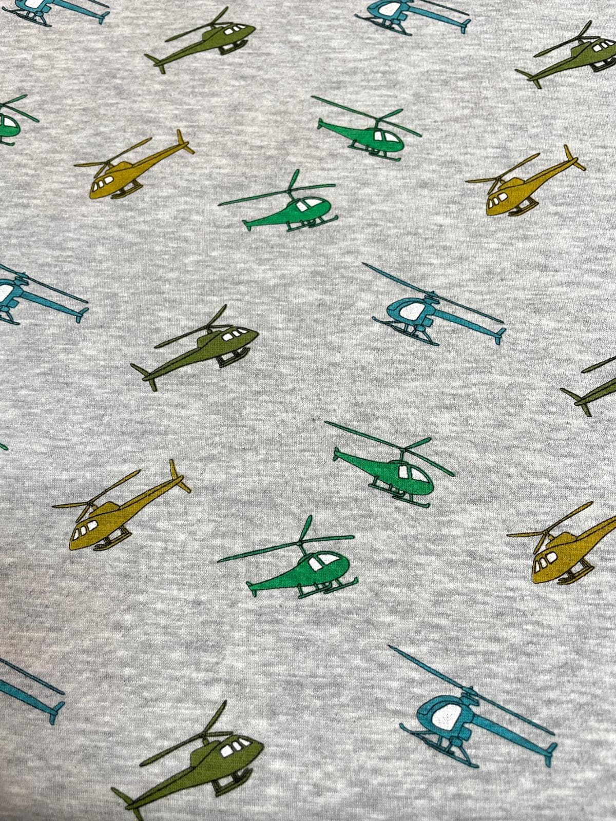 Weicher Alpenfleece in Grau Meliert mit bunten Hubschrauber-Motiven in Grün, Blau und Gelb; Doubleface-Qualität mit flauschiger Rückseite, ideal für warme Kinder-Hoodies und Jacken.