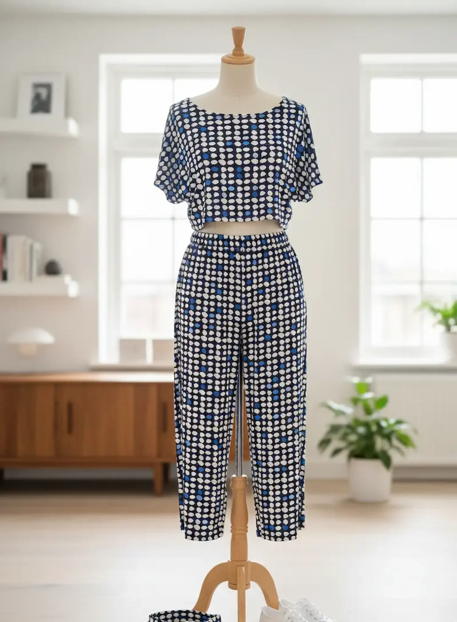 Ein luftiger, selbstgenähter Sommer-Zweiteiler bestehend aus einem kurzärmeligen Crop-Top und einer locker fallenden Hose präsentiert auf einer Schneiderpuppe aus Holz. Das Set ist aus dem fließenden, dunkelblauen Viskosejersey mit dem unregelmäßigen weiß