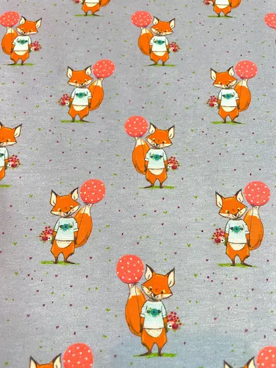 Niedlicher Jerseystoff in Hellgrau-Blau meliert mit Fuchs-Motiven, die einen roten Herz-Luftballon und Blumen halten, ideal für verspielte Kinderkleidung.