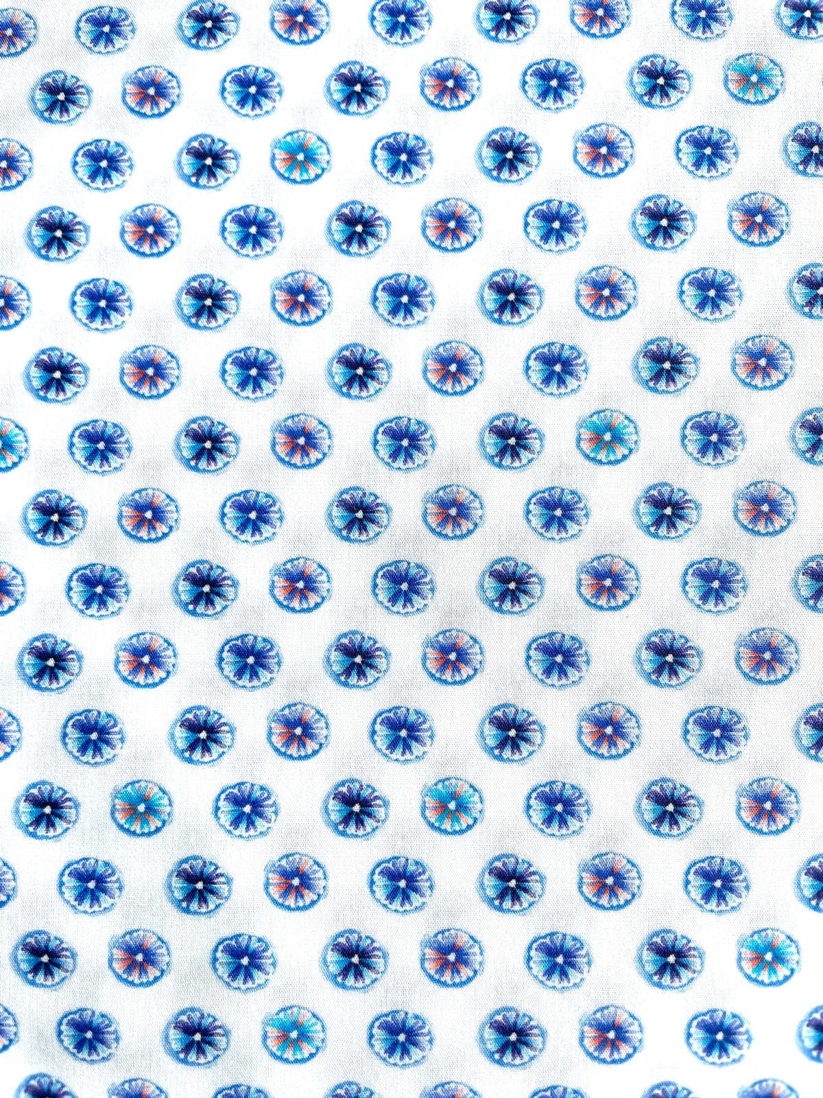 Weißer Baumwollstoff mit einem künstlerischen, blauen und violetten Muster aus abstrakten, kreisförmigen Blüten-Ornamenten.
